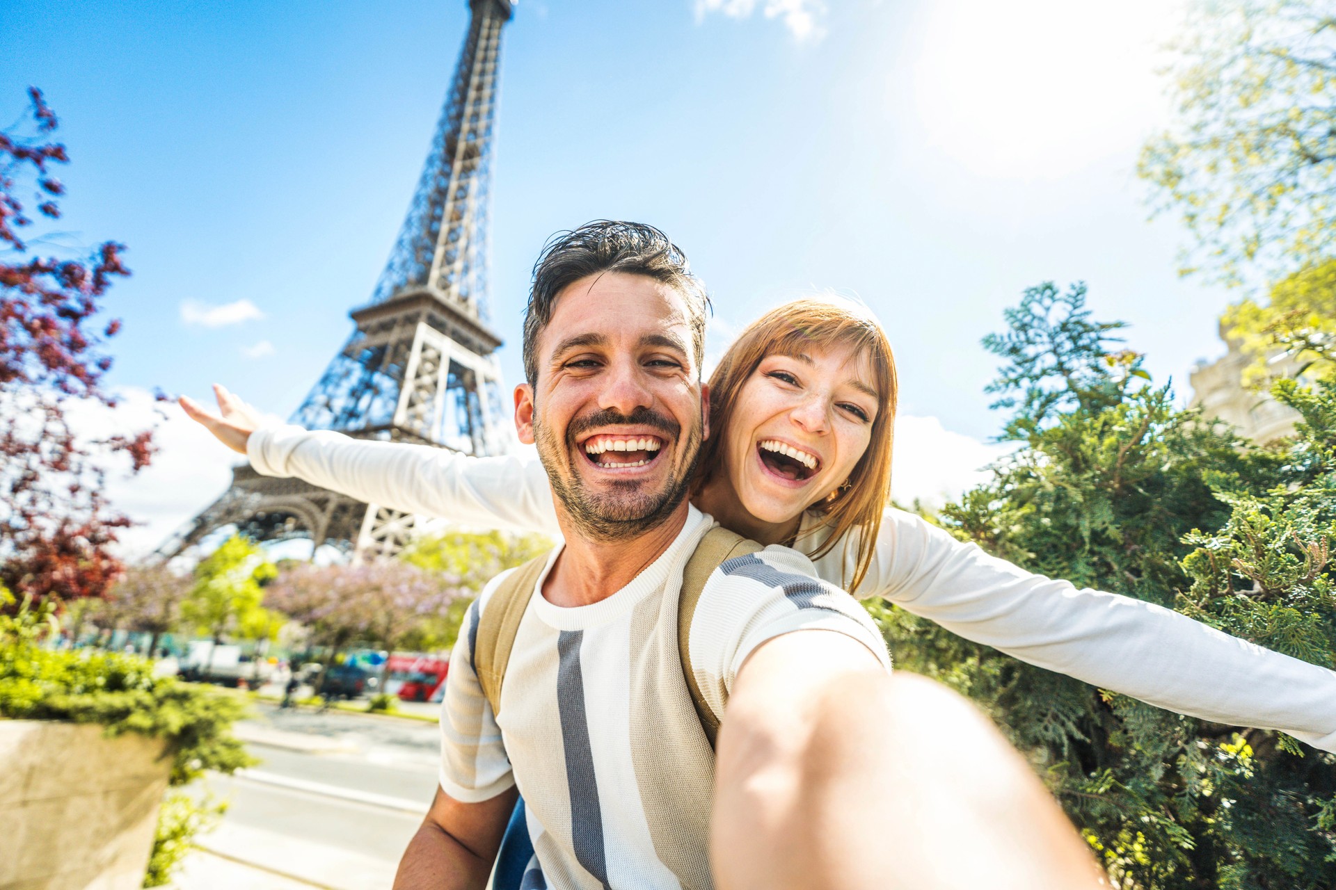 Happy couple of tourists taking selfie picture in front of Eiffel Tower in Paris, France - Travel and summer vacation life style concept